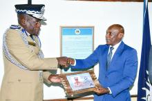 Mr. Wambura (In suit) presenting a gift to the DIG Administration, Mr. Happy Mkandawire 